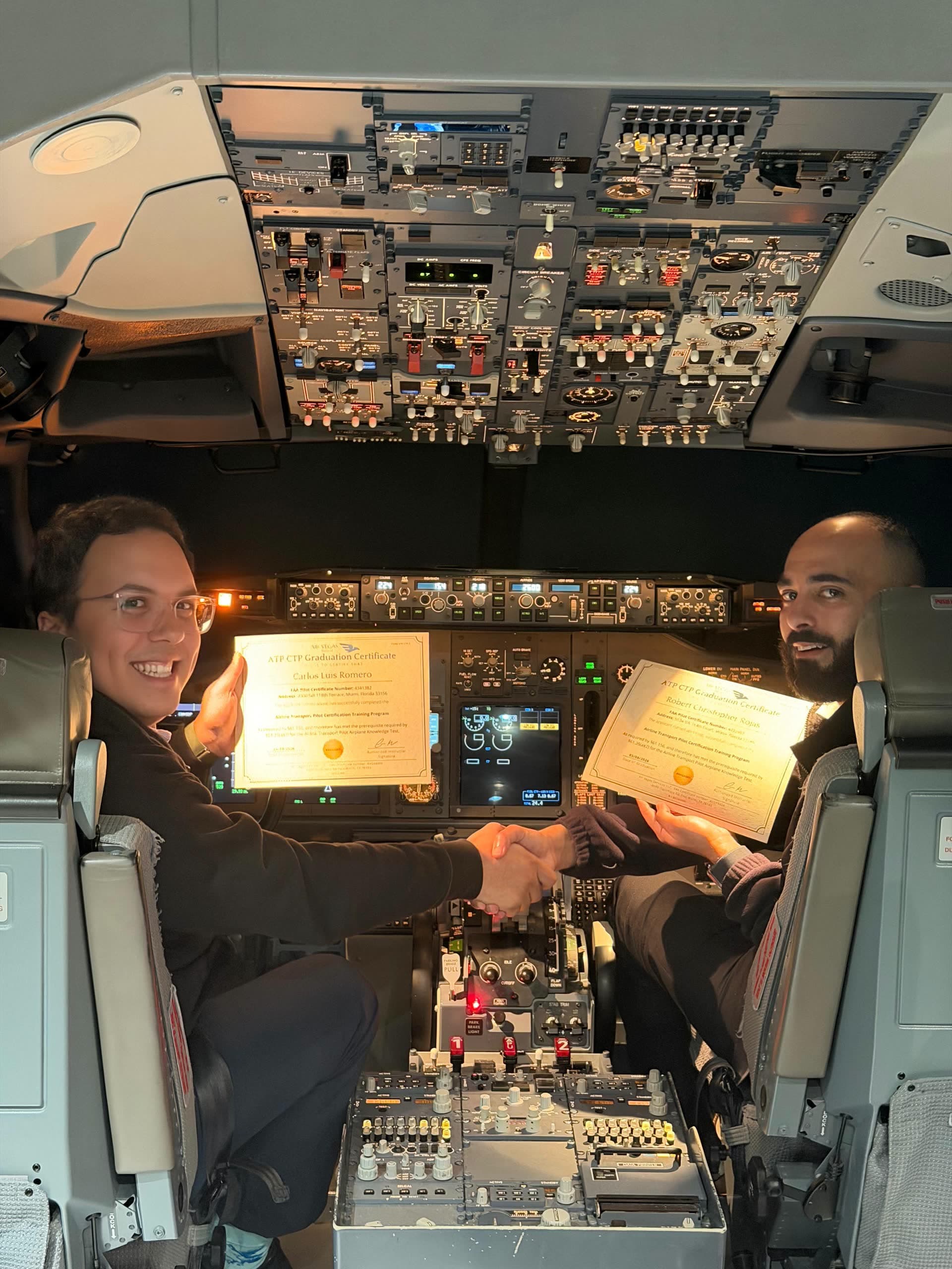 Pilots shake hands in the simulator cockpit on graduation day