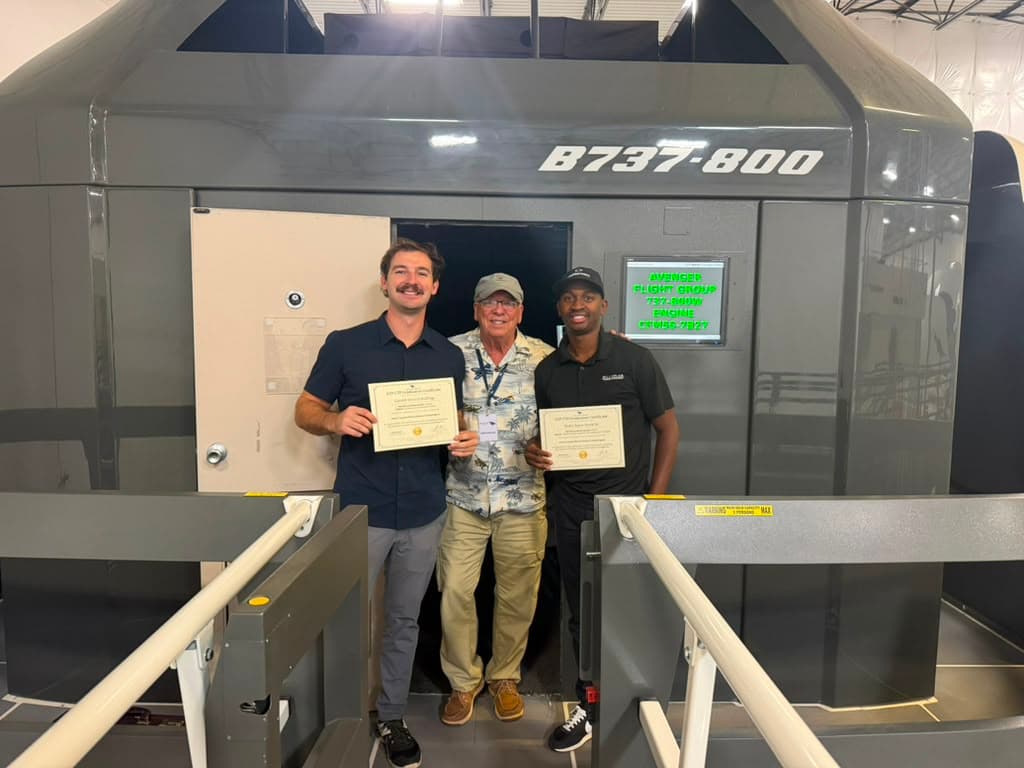 Two new ATP-CTP graduates with their instructor holding certificates at the B737-800 full-motion simulator