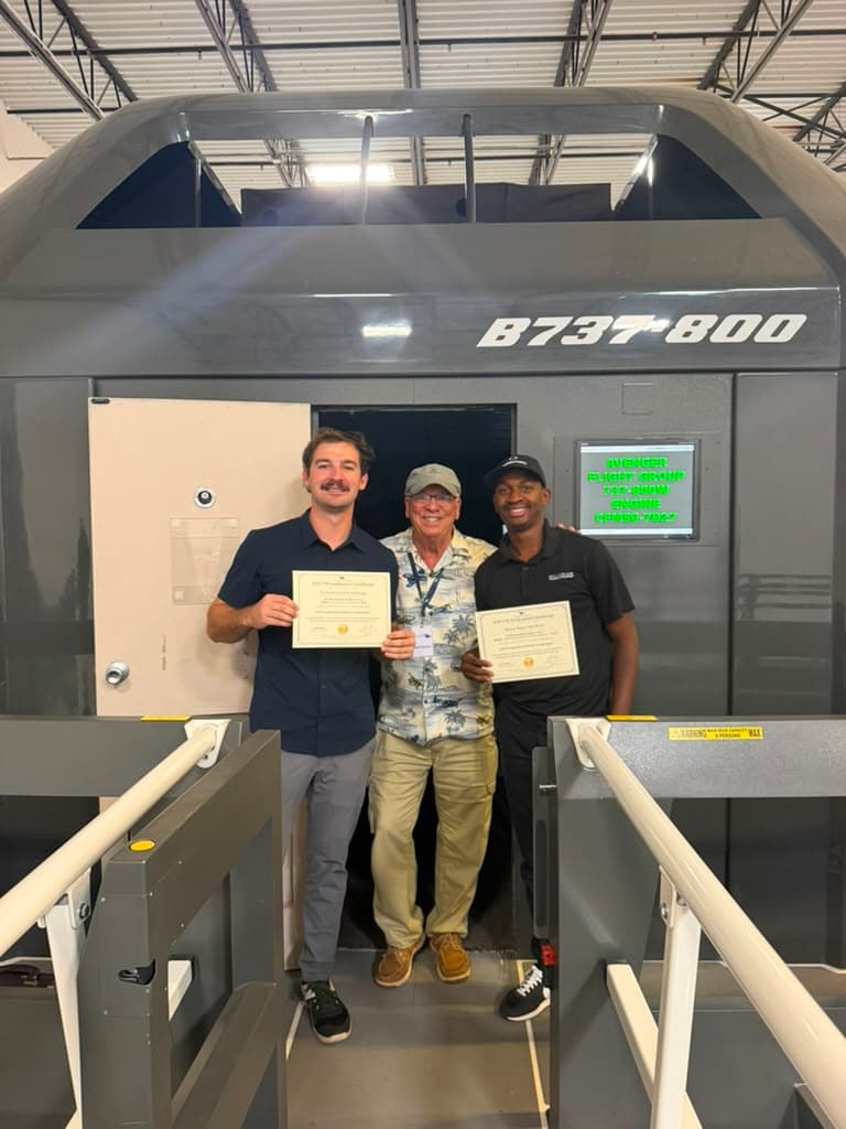 ATP-CTP graduates celebrate with certificates at the entrance of the B737-800 simulator