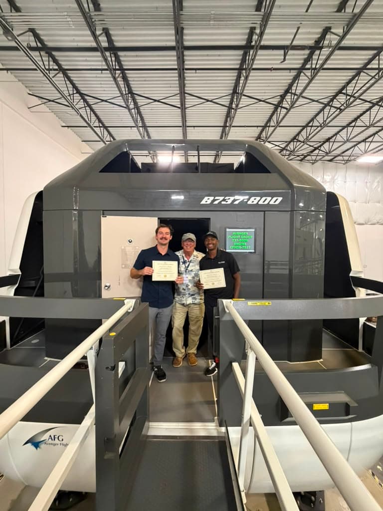 Graduates and instructor on the bridge of the B737-800 full-motion simulator on certificate day