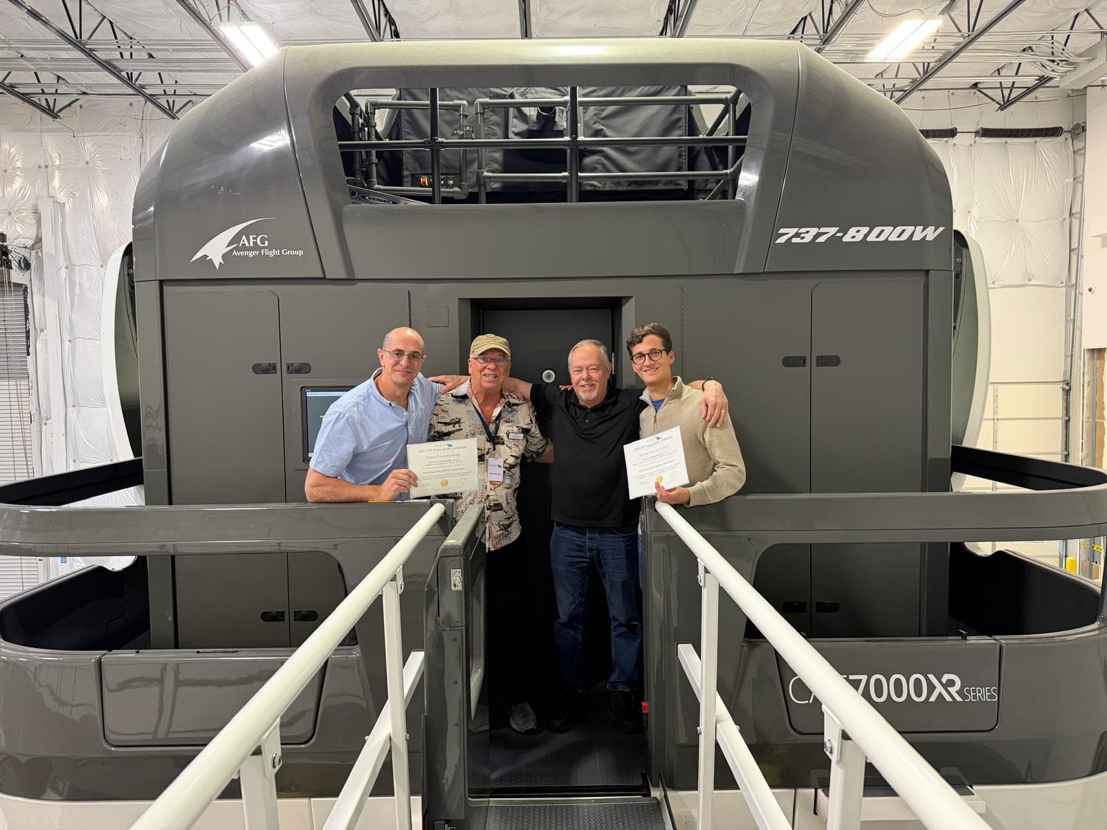 AVS graduates and instructors in front of the full-motion simulator